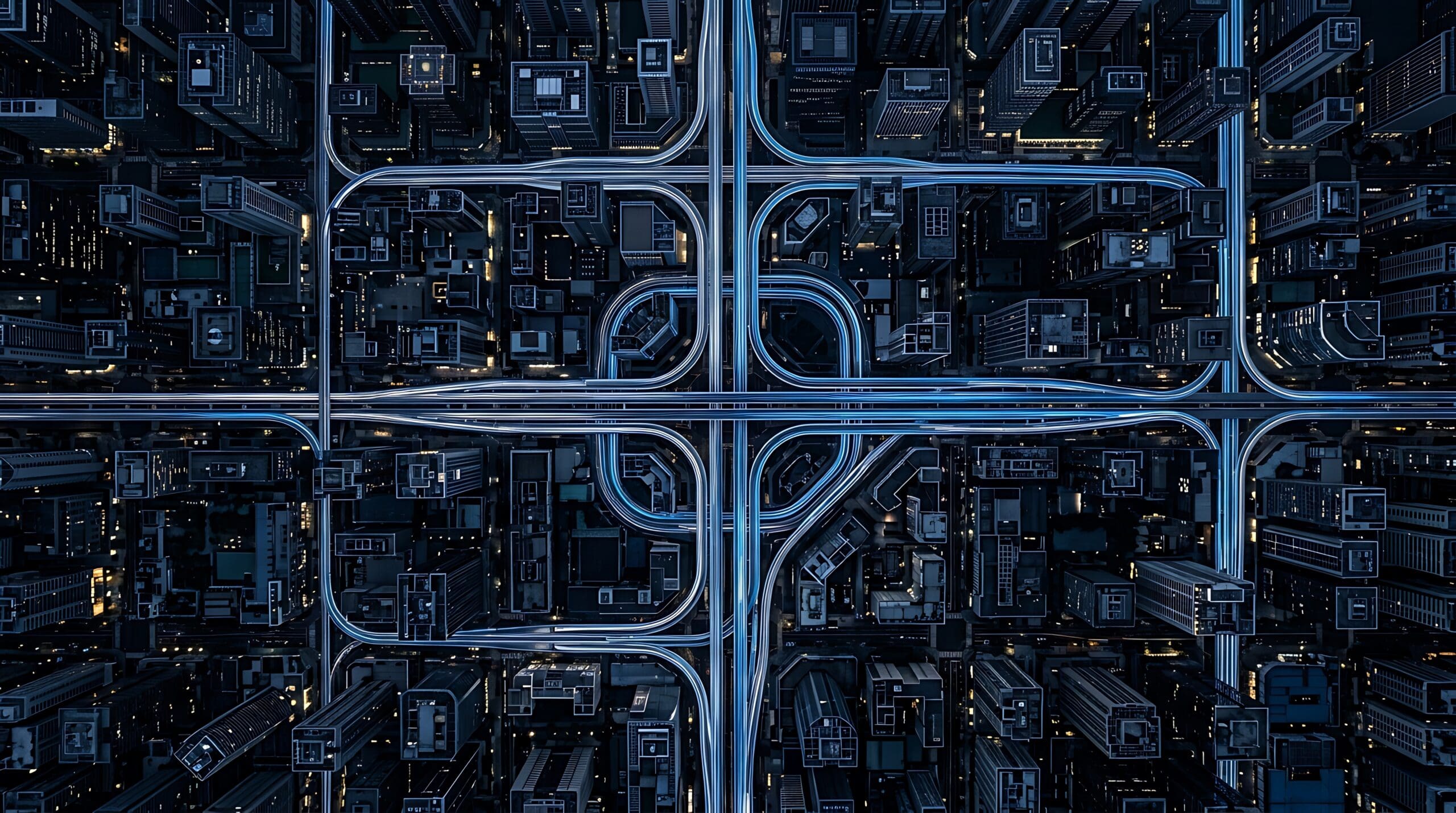 Aerial view of a complex highway interchange system glowing with blue light in a dark modern urban city